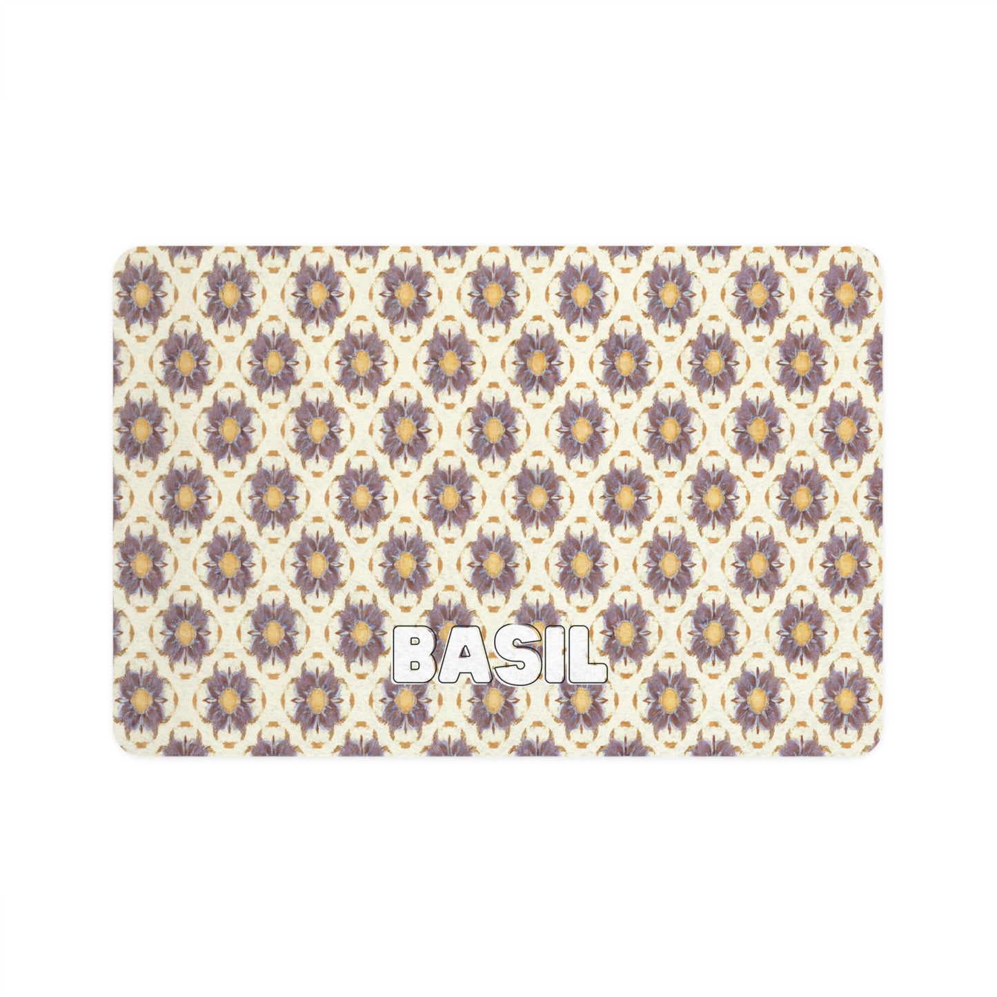 A rectangular mat with a repeating pattern of African-inspired, stylized purple and yellow flowers on a cream background. The word BASIL is written in bold, white, uppercase letters near the bottom left corner.