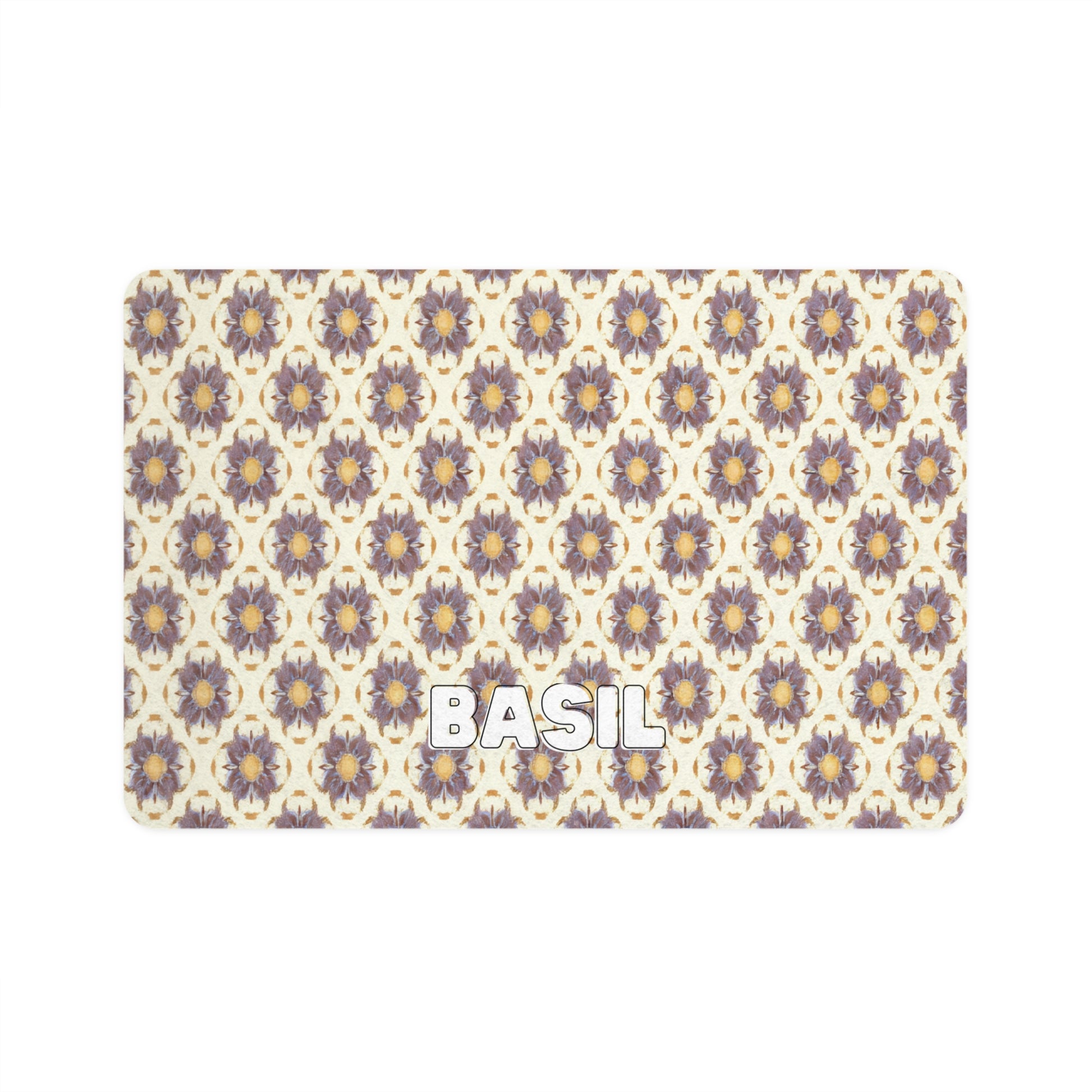 A rectangular mat with a repeating pattern of African-inspired, stylized purple and yellow flowers on a cream background. The word BASIL is written in bold, white, uppercase letters near the bottom left corner.