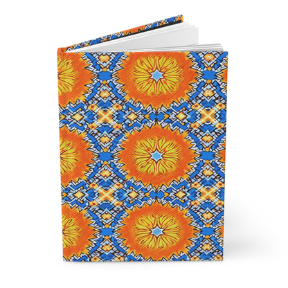 A hardcover notebook with a vibrant sunburst design, inspired by African patterns, features large orange and yellow circles surrounded by intricate blue, white, and yellow geometric shapes on a light blue background. The African-inspired journal is partially open.