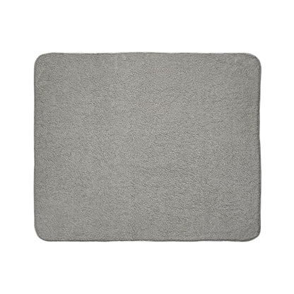 A rectangular, light gray bath mat with slightly rounded corners, made of soft, plush fabric. Subtle African-inspired elements enhance its even texture and simple, unembellished design, showcased flat against a white background.