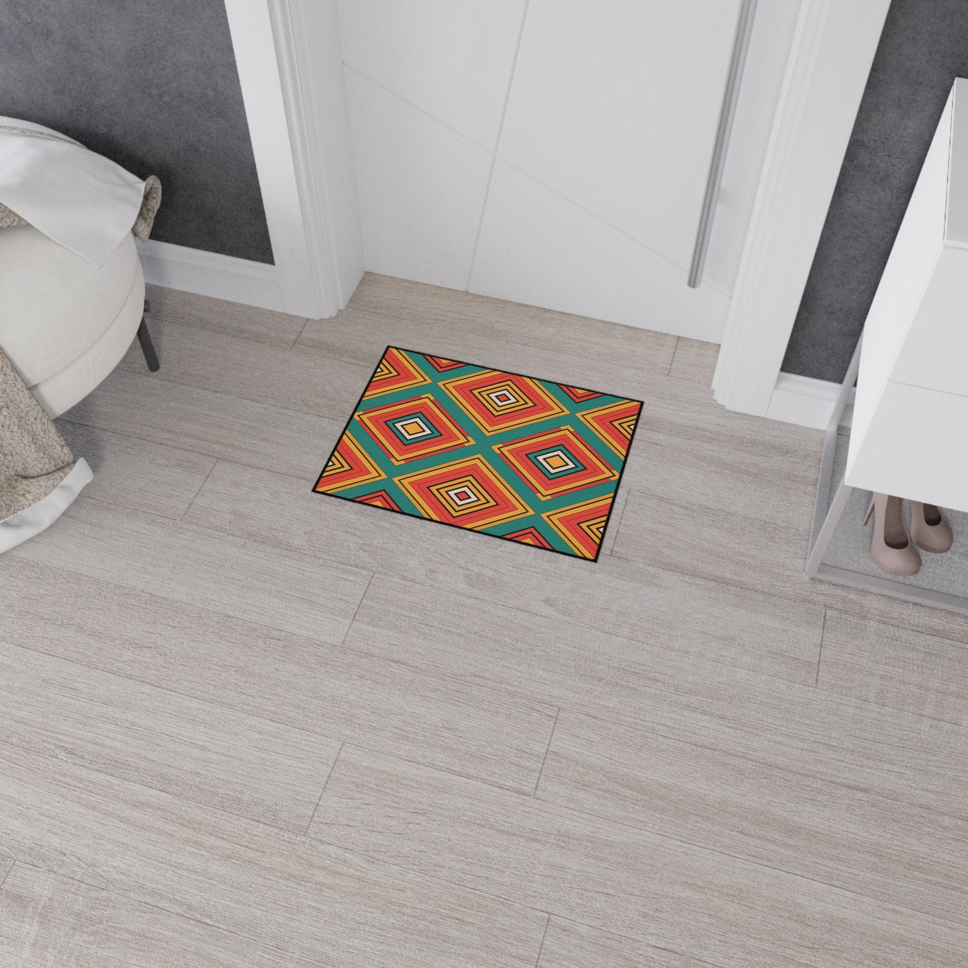 A colorful rectangular rug with an African-inspired geometric diamond pattern in red, orange, yellow, blue, and green lies on a light wood floor near a white door. A white tufted chair and a shoe rack with beige high heels are visible nearby.