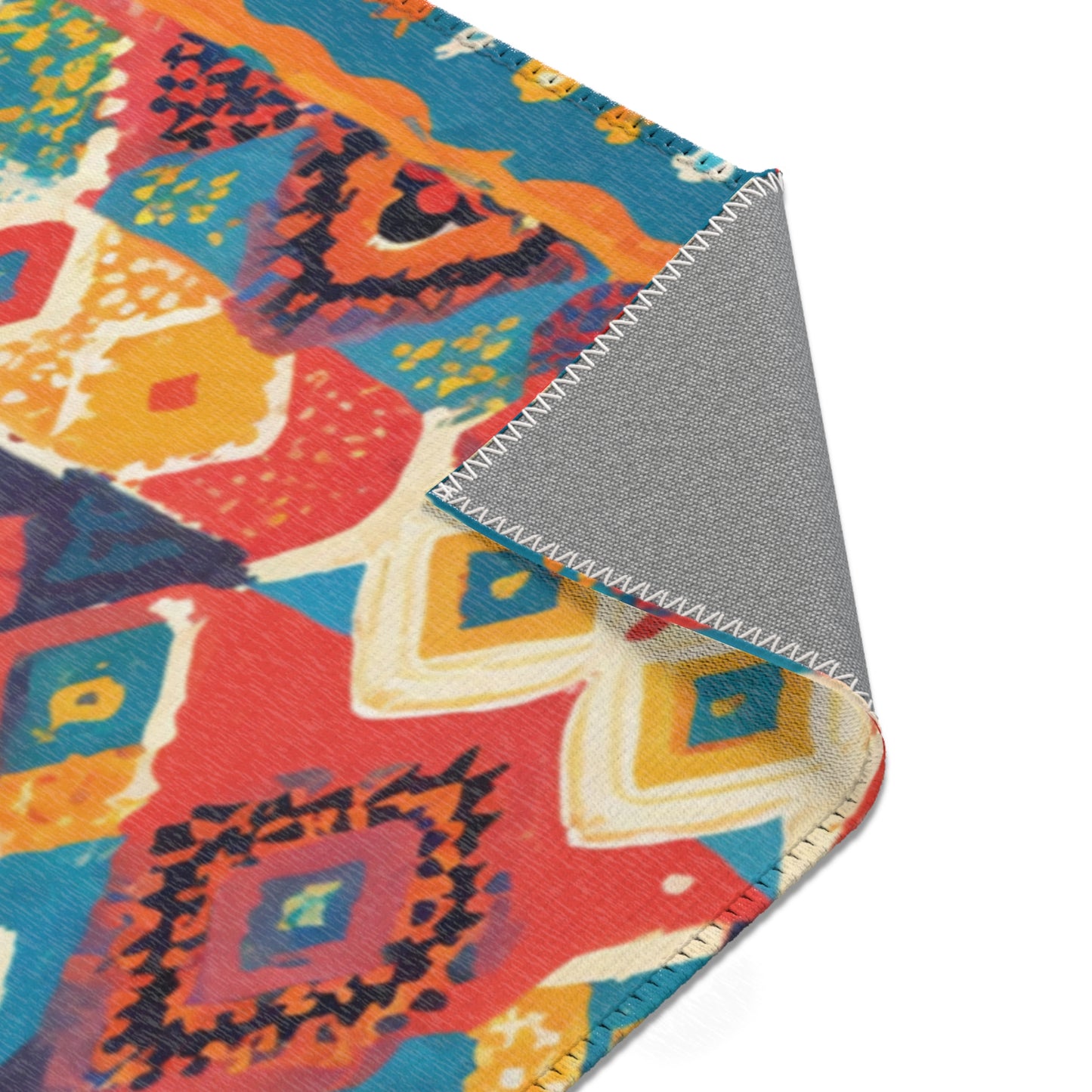 A colorful woven textile with a geometric diamond pattern in red, orange, yellow, blue, and teal. One corner is folded over to reveal a plain gray underside with white zigzag stitching—an ideal choice for stylish home decor. The background is white.