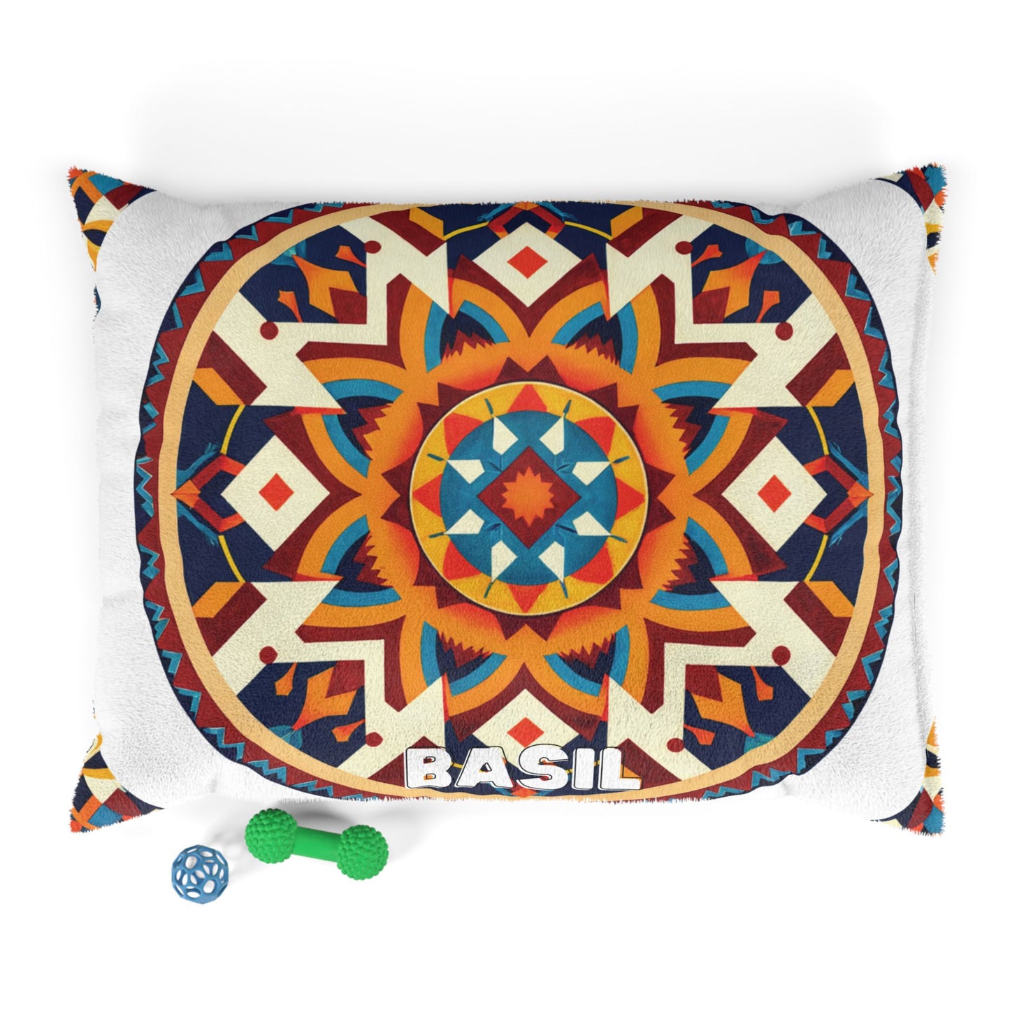 A rectangular pillow features a vibrant, symmetrical geometric mandala in red, orange, teal, yellow, and navy. “BASIL” is printed in bold white letters at the bottom. This personalized pet bed offers durable construction for lasting use. Two small dog toys—a blue ball and a green bone—are placed nearby on a white background.