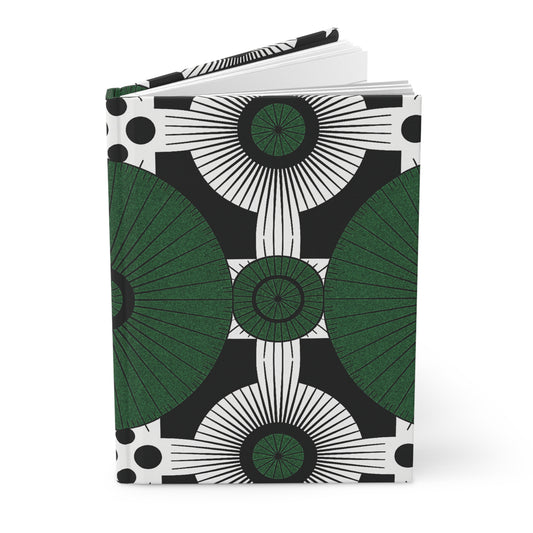 A hardcover notebook with a bold, geometric cover design featuring green semicircles, black and white radiating lines, concentric circles, and large black dots—an African-inspired journal with lined pages on a crisp white background in a symmetrical pattern.