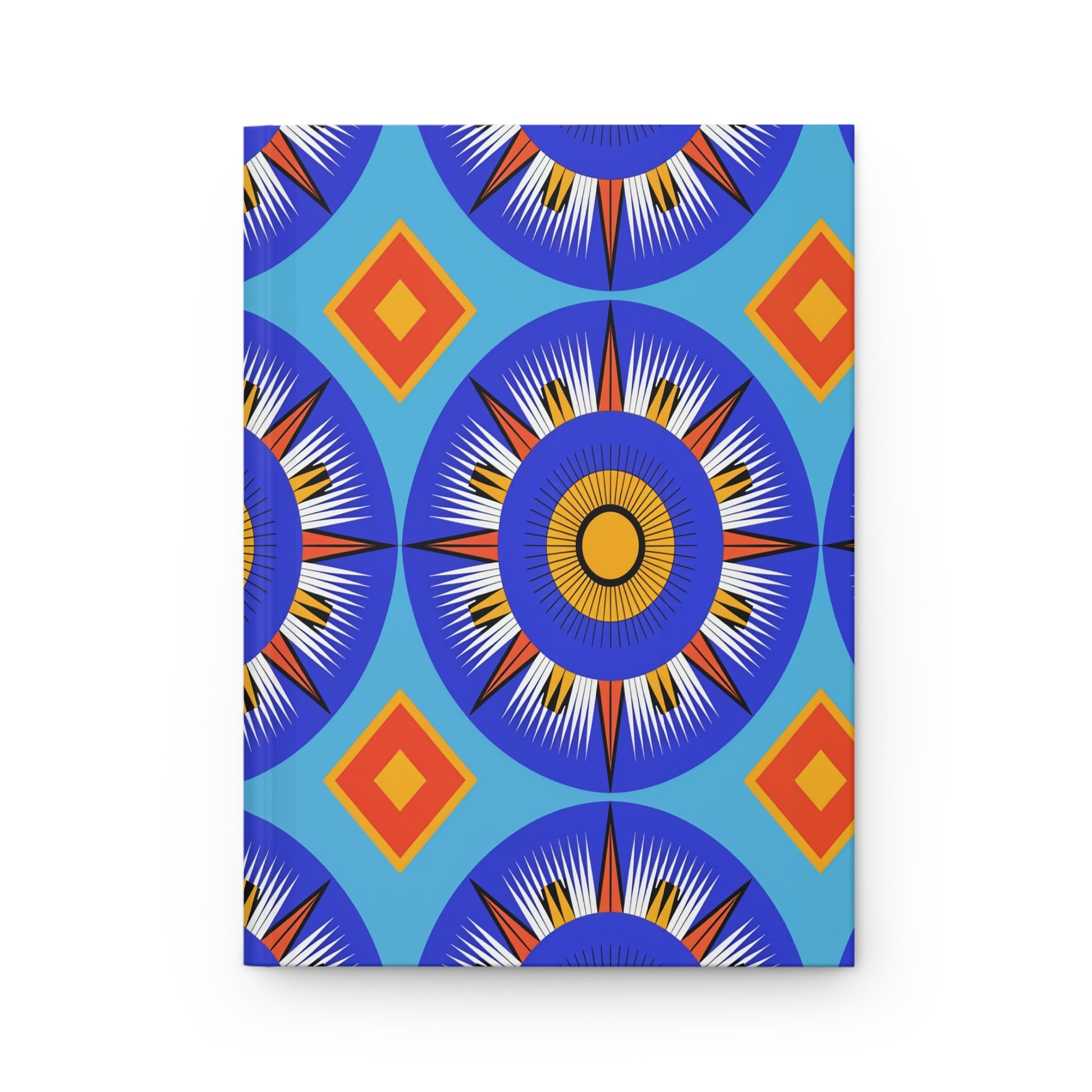 A vibrant geometric pattern featuring large blue circular sunburst shapes with white, black, and yellow rays adorns this African-inspired journal. Orange and yellow diamond shapes on a light blue background create a striking, symmetrical design.