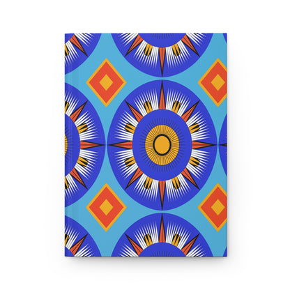 A vibrant geometric pattern featuring large blue circular sunburst shapes with white, black, and yellow rays adorns this African-inspired journal. Orange and yellow diamond shapes on a light blue background create a striking, symmetrical design.