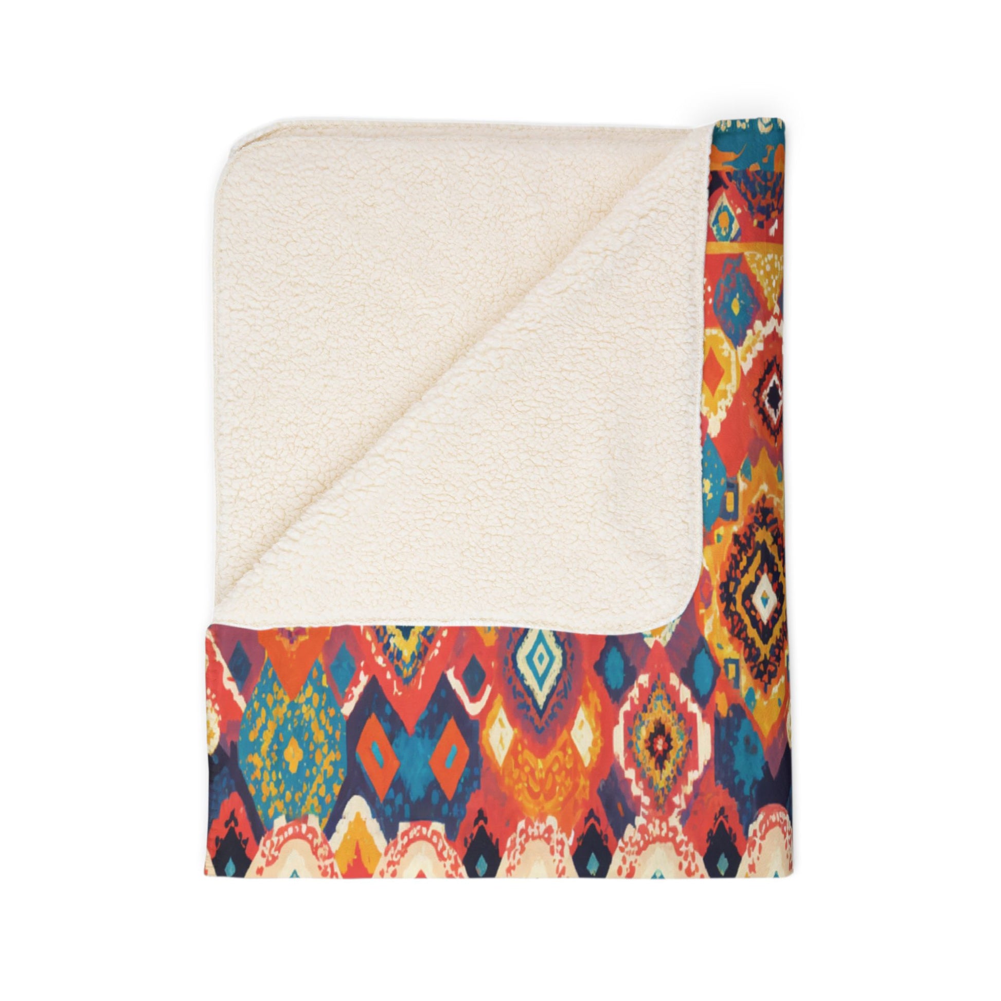 A fleece blanket folded to show both sides: one side is soft cream sherpa, the other features a vibrant, African-inspired geometric pattern in red, yellow, blue, and orange tones. The blanket’s corner is folded over, revealing the dual textures.