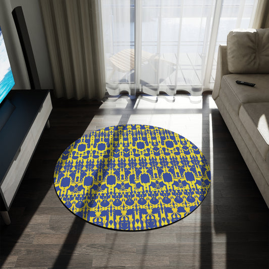 A round rug featuring vibrant designs in blue and yellow abstract geometrics, crafted from durable polyester chenille, sits on a dark wood floor in a sunlit living room near a beige sofa, TV, and large windows with sheer curtains.