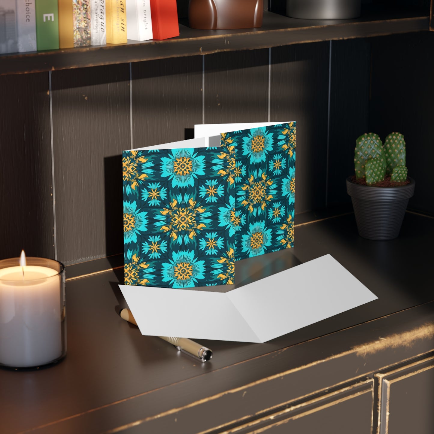 A premium stationery greeting card with a vibrant blue and yellow geometric floral pattern, inspired by culturally inspired designs, stands open on a dark shelf. Warm light and cozy surroundings enhance its inviting presence.