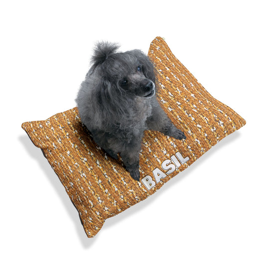 A small, curly-haired gray dog sits on a stylish dog bed with a brown pattern and BASIL written in white capital letters — the perfect personalized pet bed against a plain white background.