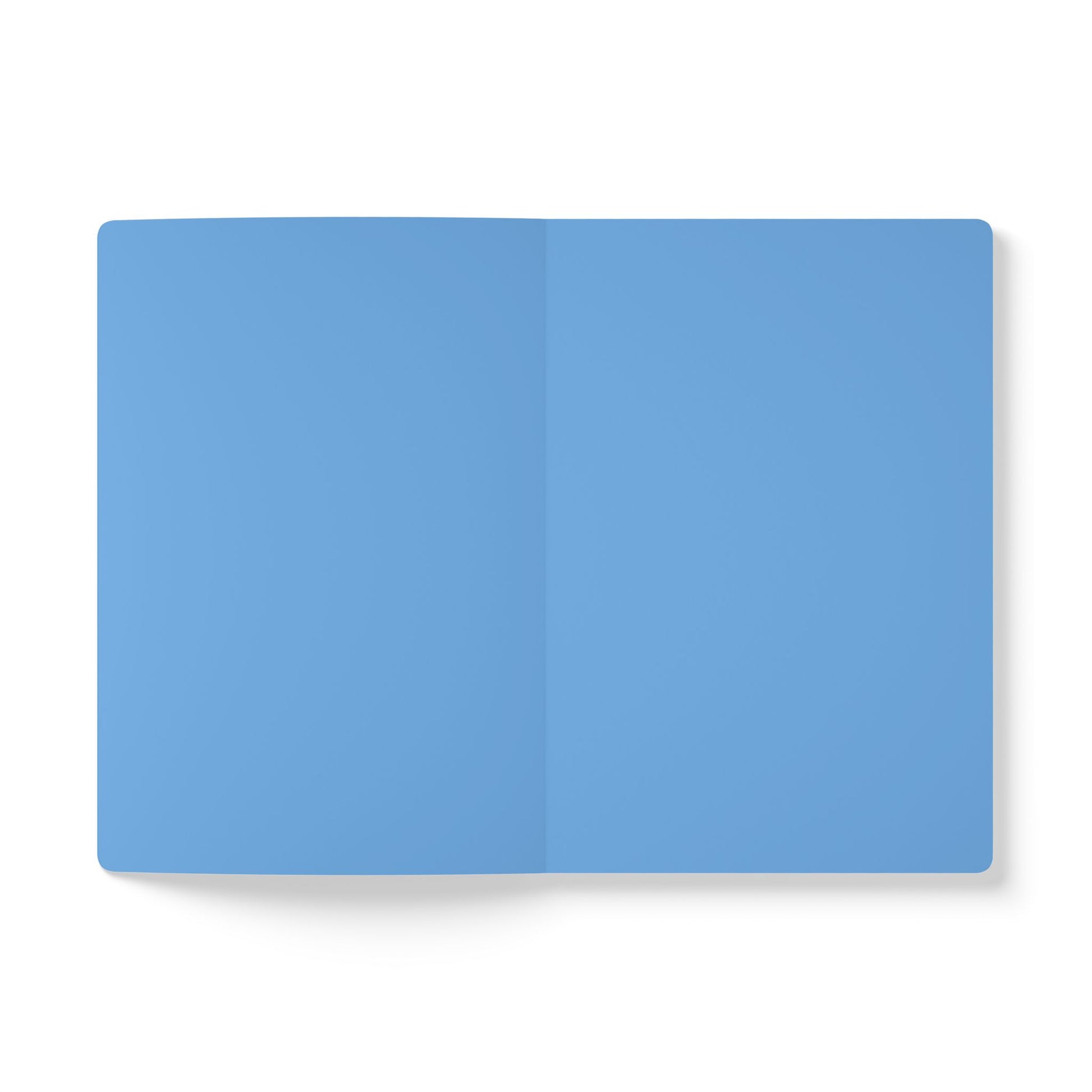 A top-down view of an open creative journal with blank, light blue pages. The journal lies flat on a white background, featuring a visible vertical crease in the center where the pages meet. No text, lines, or images appear on the pages.
