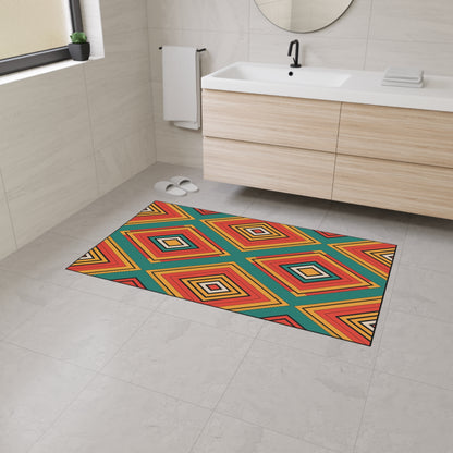A modern bathroom with light beige tiles, a wooden vanity with a white sink, a round mirror, and an African-inspired geometric bath mat featuring red, yellow, orange, blue, and green diamond patterns on the non-slip rubber backing floor. White slippers are near the vanity.