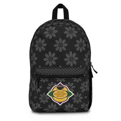 A black, African-inspired backpack with gray floral patterns, a front zip pocket, and a side mesh pocket. The front pocket features a colorful oval patch reading Afro Comfort Shop, echoing the Pan-African flag and celebrating culturally inspired designs.