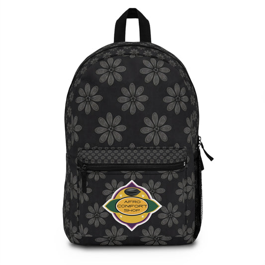 A black, African-inspired backpack with gray floral patterns, a front zip pocket, and a side mesh pocket. The front pocket features a colorful oval patch reading Afro Comfort Shop, echoing the Pan-African flag and celebrating culturally inspired designs.