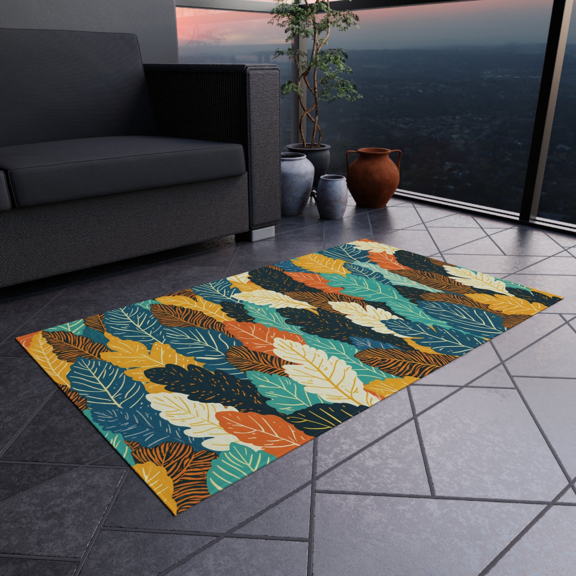 A colorful, African-inspired rug with a bold leaf pattern in yellow, orange, teal, blue, and green lies on a tiled balcony floor. Nearby are a dark sofa, two ceramic pots, a small plant, and a glass railing overlooking a cityscape at sunset.
