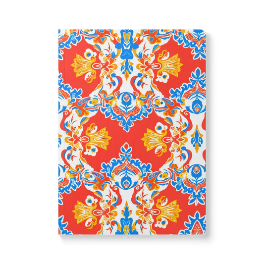 A creative journal with a vibrant, symmetrical floral pattern in red, blue, yellow, and white. The bold design features ornate flowers and leaves, creating a lively motif on the cover—perfect for daily journaling or as an African-inspired journal.
