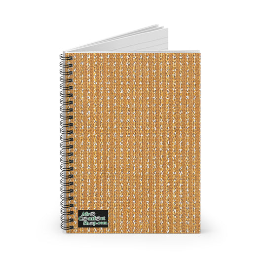 A spiral-bound notebook stands upright with a cover design resembling woven burlap in tan and beige tones, reflecting culturally inspired designs. A small label at the bottom left reads Moo Confident Shop.com in green and white. The pages are slightly open.