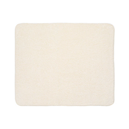 A rectangular, cream-colored, plush bath mat with softly rounded corners and a uniform, fluffy texture is shown against a white background. Its cozy look is enhanced by subtle African-inspired detailing for a unique touch.