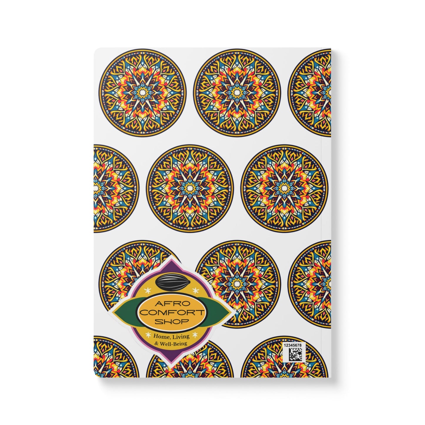 A white notebook cover features a repeating pattern of colorful, intricate circular mandala designs. Perfect as an African-inspired journal, it has a gold, green, and purple label with Afro Comfort Shop: Home, Living & Well-Being and a small QR code.