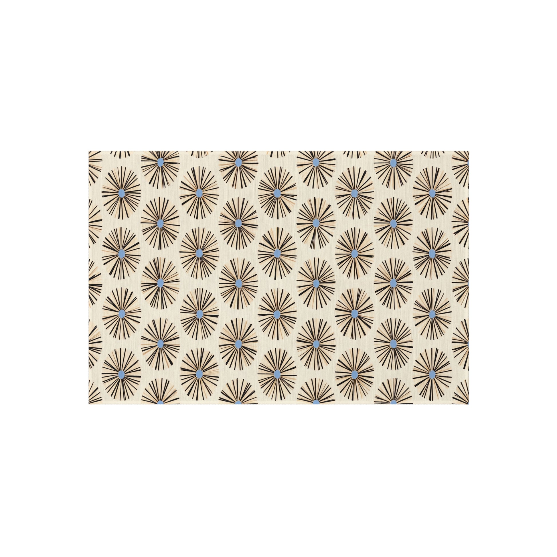 A beige rectangular surface features a repeating pattern of black starburst shapes with light blue centers, inspired by authentic African art designs. The geometric, mid-century modern look is enhanced by weather-resistant polyester chenille.