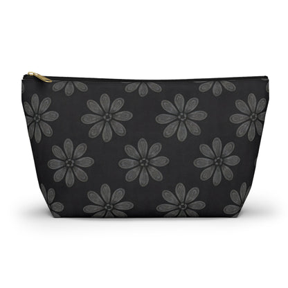 A black T-bottom pouch with a gold zipper, featuring African-inspired patterns of large, stylized gray flowers with petal details evenly spaced across the surface. This cosmetic travel bag is photographed against a white background.
