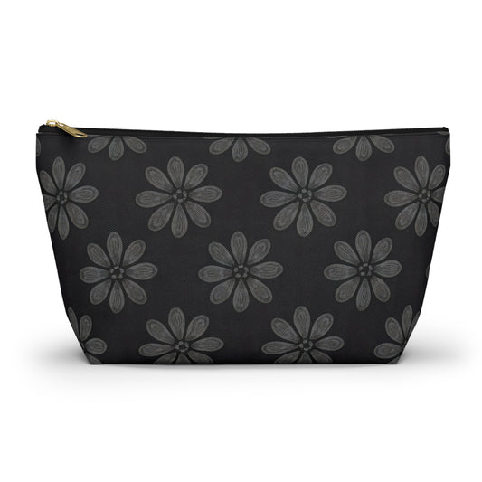 A black T-bottom pouch with a gold zipper, featuring African-inspired patterns of large, stylized gray flowers with petal details evenly spaced across the surface. This cosmetic travel bag is photographed against a white background.