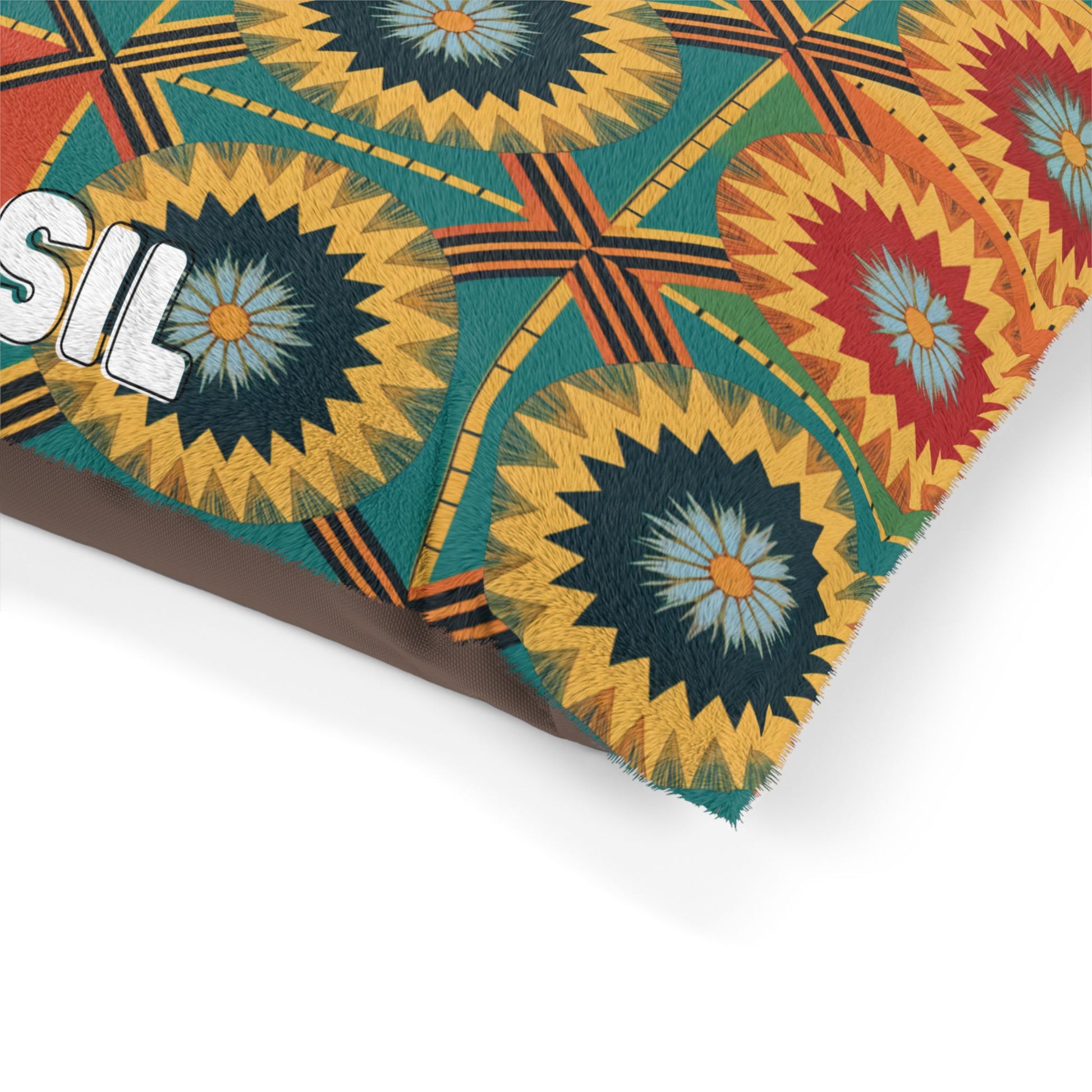 A close-up of a Personalized Pet Pillow featuring a colorful geometric pattern with sunburst shapes in yellow, red, blue, and green. Visible stitching details and part of the word “SIL” in bold white letters enhance its stylish appeal.