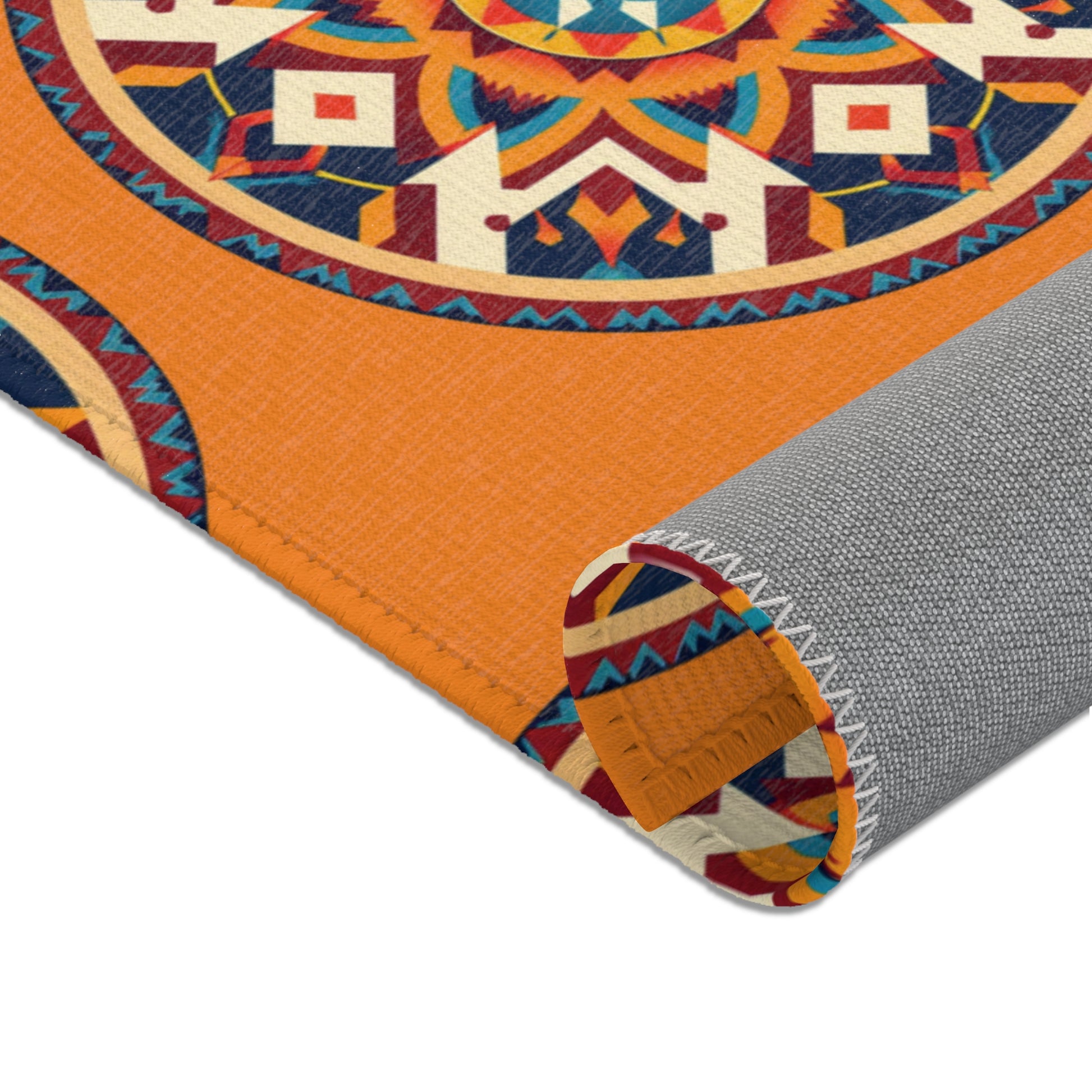 A close-up of a rolled-up orange mat featuring an African-inspired, vibrant geometric mandala pattern in blue, red, yellow, and white. The mat’s stitched edge and textured gray underside highlight its durability and colorful design.