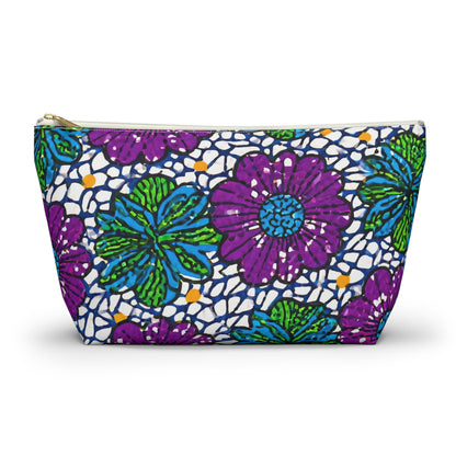 A zippered cosmetic travel bag featuring a vibrant floral pattern with large purple flowers, green and blue leaves, and a white background with navy blue accents. This T-bottom pouch stands upright and has a gold zipper at the top.