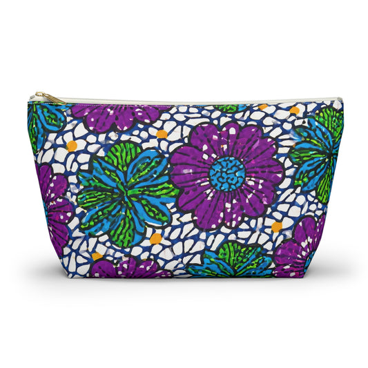 A zippered cosmetic travel bag featuring a vibrant floral pattern with large purple flowers, green and blue leaves, and a white background with navy blue accents. This T-bottom pouch stands upright and has a gold zipper at the top.