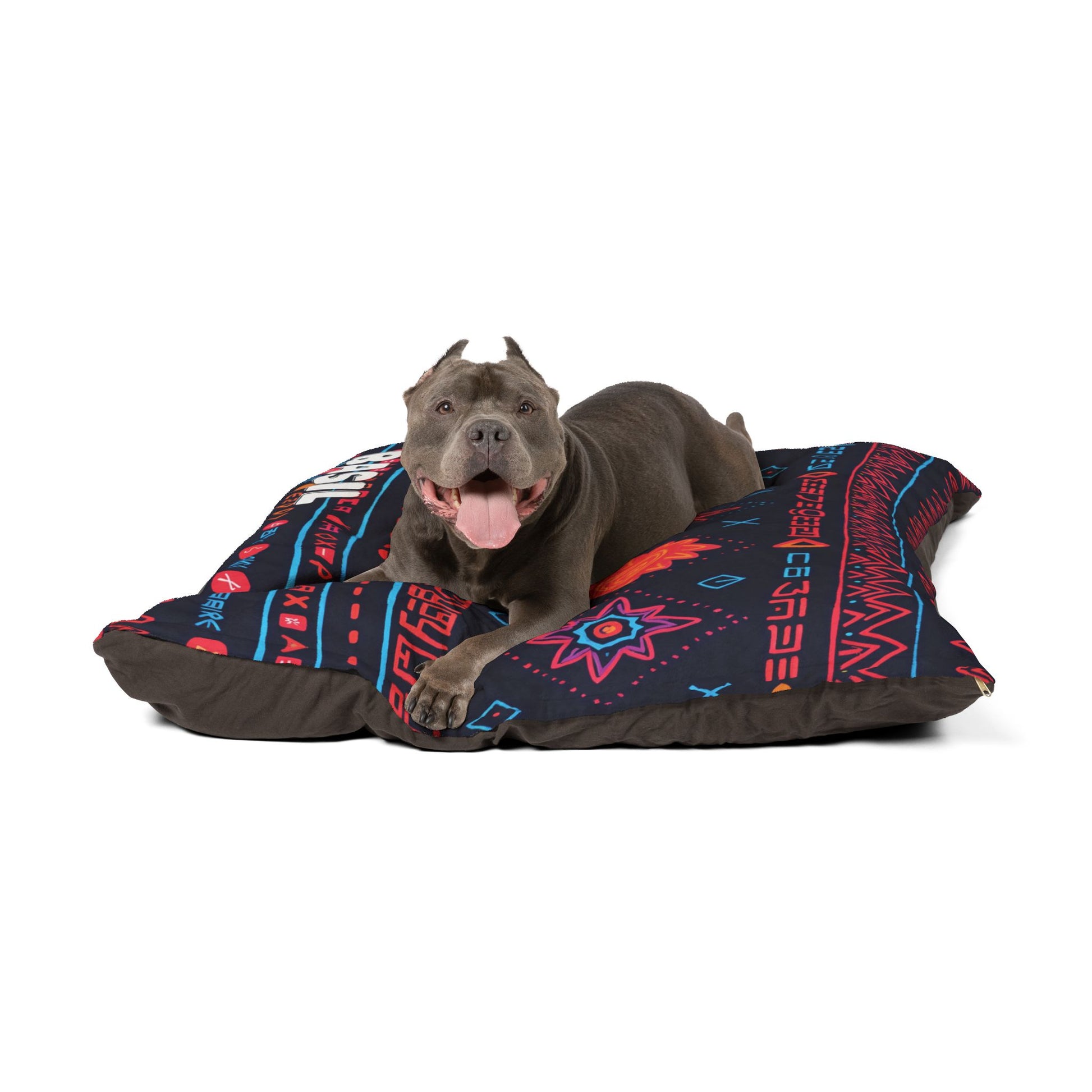 A gray dog with cropped ears and a red collar lies on a large black cushion with colorful, geometric Southwestern patterns. This personalized pet bed offers luxurious comfort, as the happy pup faces forward with its mouth open and tongue out.