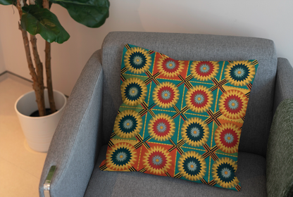 A square pillow with vibrant patterns and a colorful geometric starburst design in yellow, red, green, and blue rests on a light gray armchair. A green plant in a white pot sits nearby, adding charm to this inviting home decor scene.