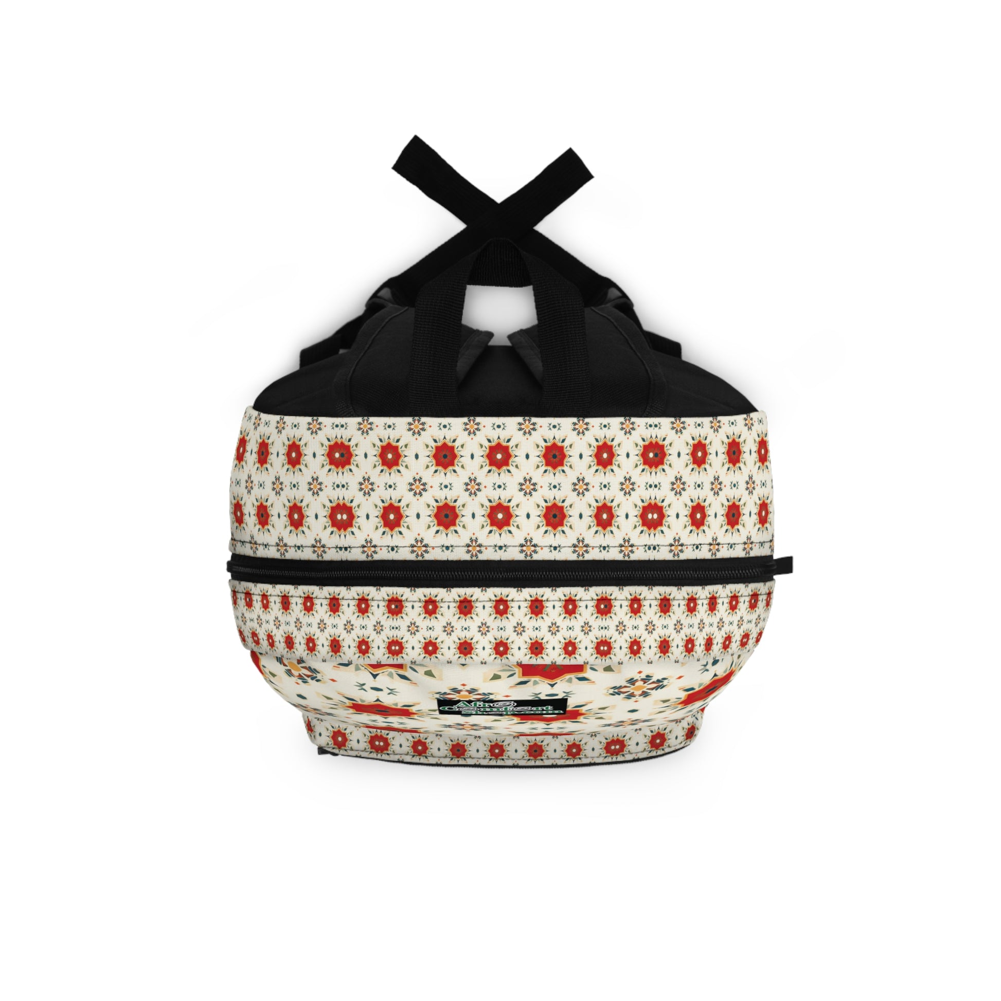 A round duffel bag with black handles and a zipper, featuring a red, orange, and cream floral and geometric pattern. This boho chic rucksack has a small black tag on one side and a cream base with repeated rows of flower motifs.