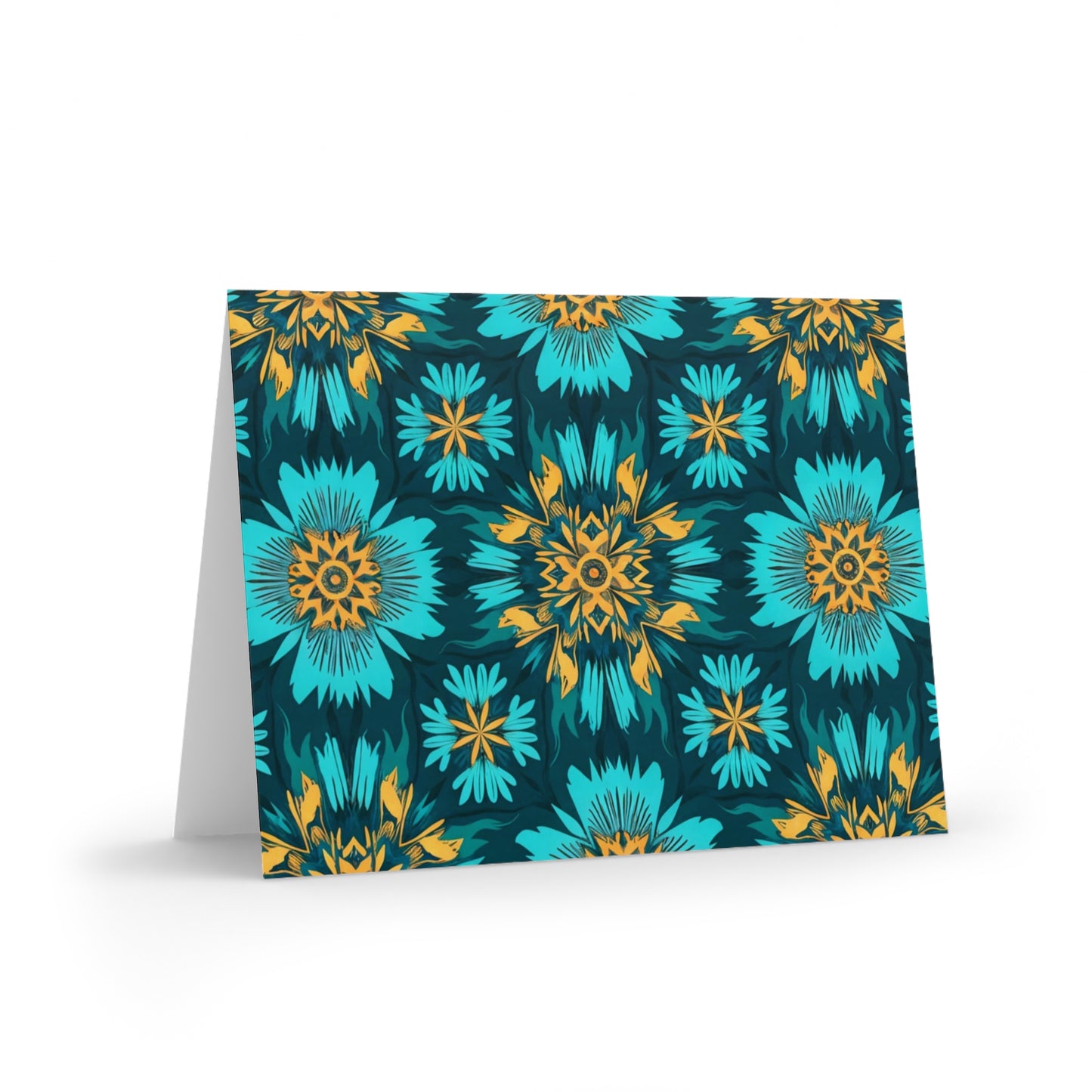 A folded greeting card stands open, featuring a vibrant floral pattern with large blue and orange flowers and smaller yellow accents, set against a dark teal background. This African-inspired greeting card has a bold, symmetrical, and geometric feel.