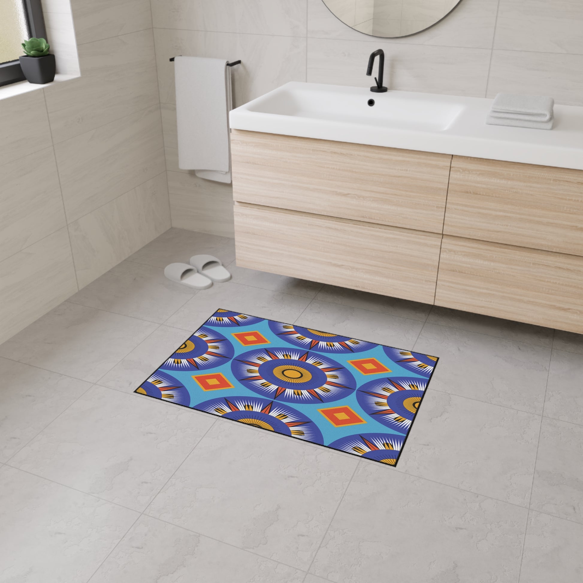 A modern bathroom with light wood vanity, white sink, black faucet, and round mirror. Custom floor mats with colorful geometric patterns and non-slip rubber backing add African-inspired aesthetics to the tiled floor. White slippers rest near a window.