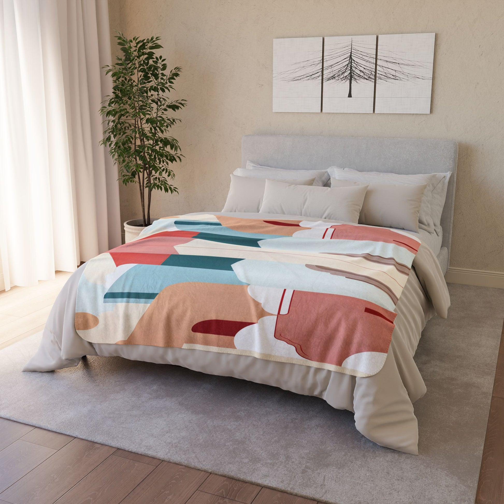 A neatly made bed with a colorful, African-inspired abstract-patterned comforter stands in a cozy bedroom. A plant is in the corner, sheer curtains cover a window, and two minimalist tree artwork panels hang above the light gray headboard.