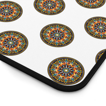 A close-up of a neoprene desk mat with a repeating pattern of colorful, circular mandala designs. Each mandala features intricate geometric shapes in blue, orange, red, and yellow, outlined in black. The mat has a black edge.