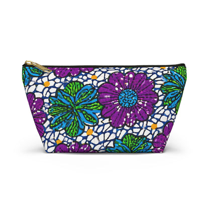 A zippered T-bottom pouch with a vibrant floral pattern featuring large purple flowers, green leaves, and blue accents. The white background showcases African-inspired patterns with small black-outlined shapes and scattered orange details—perfect as a cosmetic travel bag.