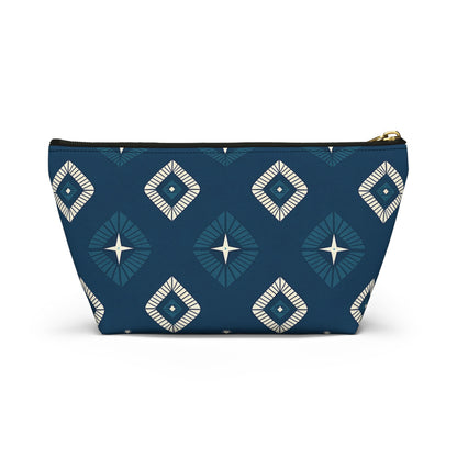 A T-bottom pouch with a geometric diamond pattern in teal, navy blue, and white. The African-inspired patterns feature starburst centers and radiating lines on a deep blue background. Gold zipper hardware lets this cosmetic travel bag stand upright.