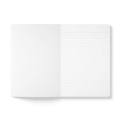 An open travel diary viewed from above on a white background; the left page is blank, and the right page features evenly spaced horizontal lines. Both pages are clean and unused, ready for your daily journaling adventures.