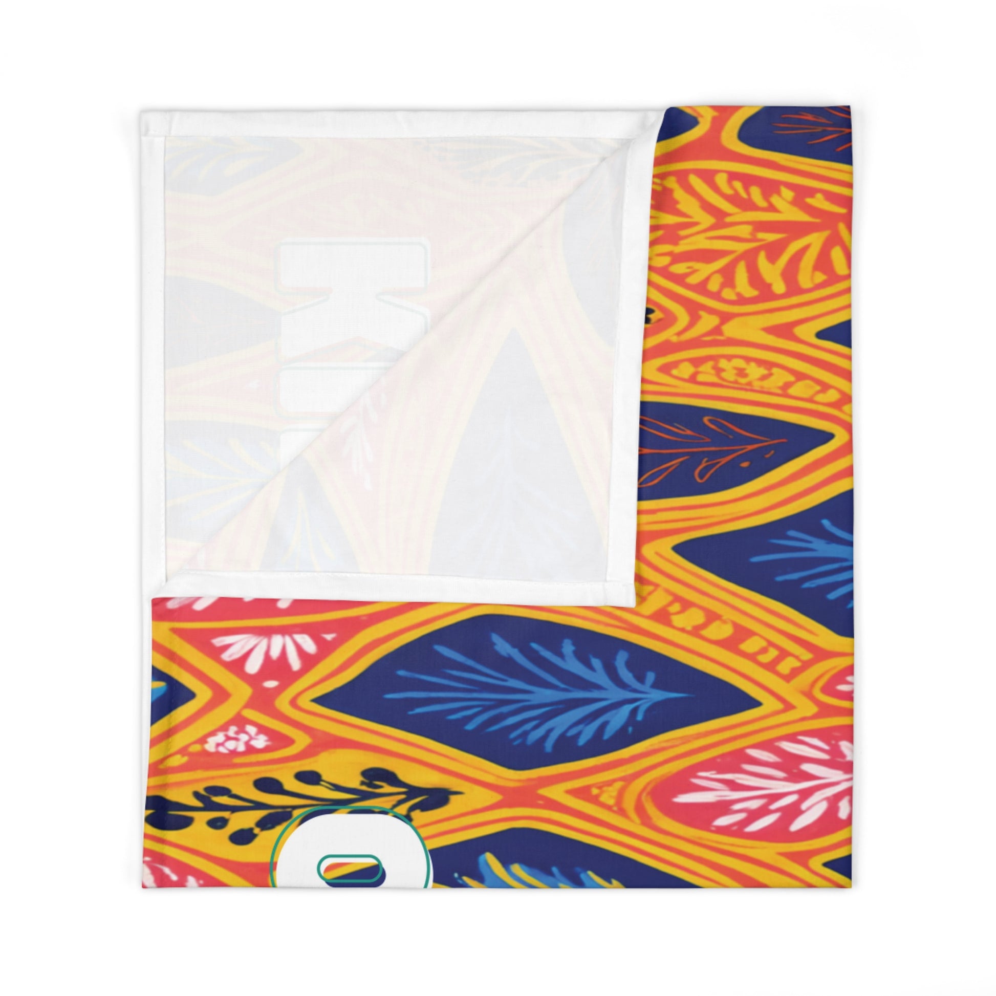 A folded rectangular fabric with a vibrant pattern of blue, pink, and yellow leaves on an orange background adds a touch of African-inspired decor. A corner is turned up, revealing the white underside and a partial white letter O with rainbow detail at the bottom.