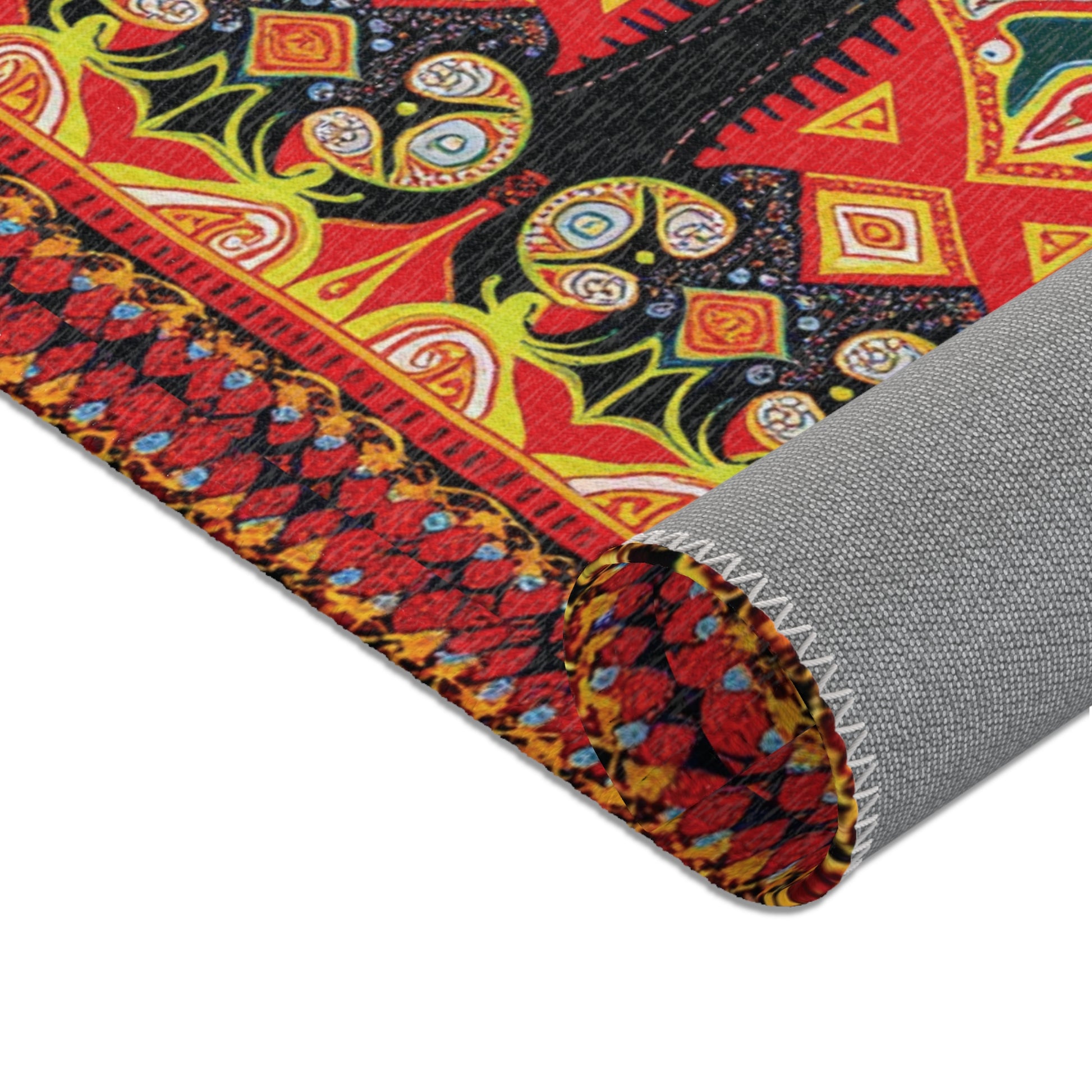 Close-up of a rolled, colorful woven fabric in the style of African design rugs, featuring intricate red, yellow, black, and green geometric and floral motifs. The reverse side is gray, highlighting the texture and stitching of the material’s edge.
