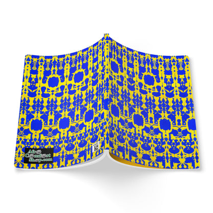 A creative journal with a bright blue and yellow intricate geometric pattern reminiscent of African-inspired designs is open, facing down. A small label in the bottom left corner reads “Art of Consent.” The background is white.