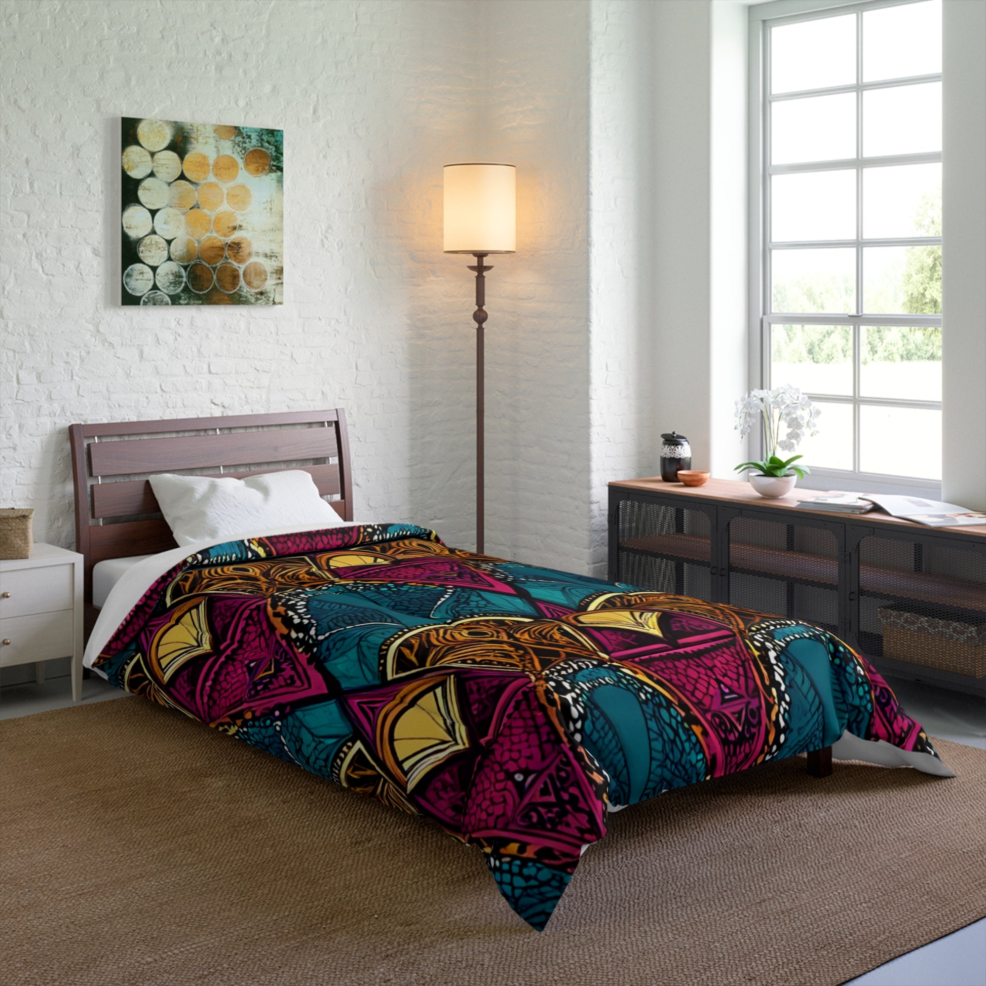 A modern bedroom with a single bed covered by a colorful African-inspired geometric-patterned comforter, a white pillow, tall floor lamp, large sunlit window, and a long console table with décor against a white brick wall.