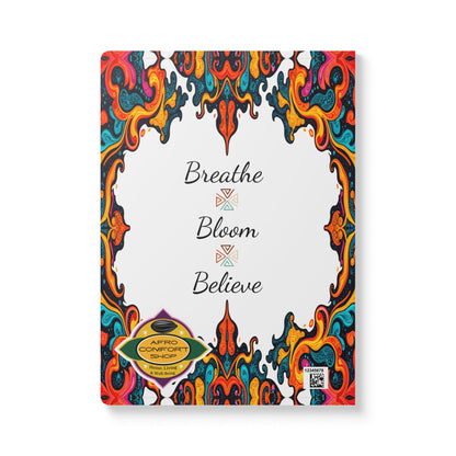 A creative journal cover featuring colorful, swirling abstract borders with a white center. "Breathe Bloom Believe" is elegantly scripted, evoking an African-inspired journal vibe. Gold Afro Comfort Shop badge and QR code complete the design.