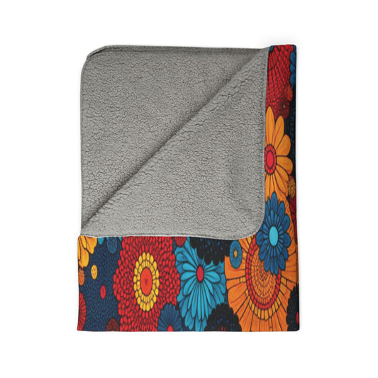 A fleece blanket with one corner folded over. The top side is solid gray and soft, while the bottom edge features a bold African-inspired floral pattern—perfect cozy home decor for a vibrant space.