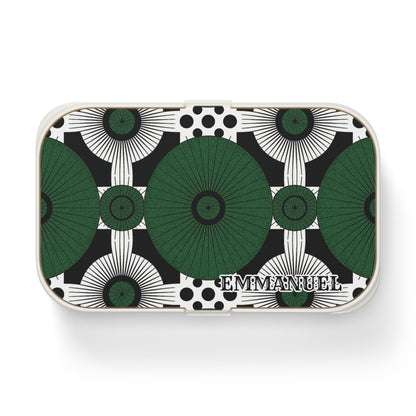 Rectangular custom lunch box with a geometric pattern of large green and black circular shapes and black dots on a white background. The bold, symmetrical design is personalized with EMMANUEL in serif letters in the lower right corner.