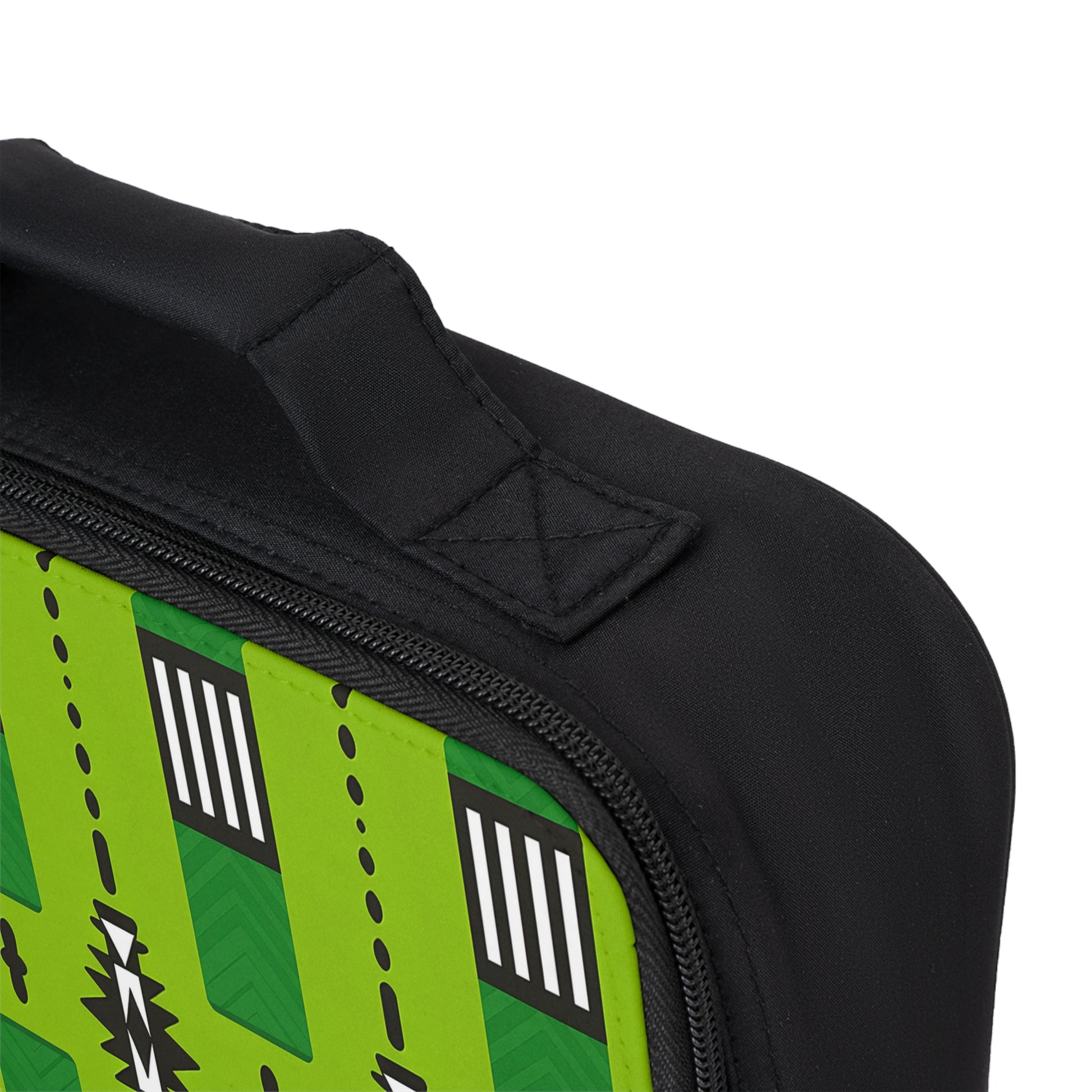 Close-up of an African-inspired lunch bag corner with a fabric handle. The side panel is bright green and features geometric black, white, and dark green patterns like stripes and zigzags. The visible zipper is black and partially open.