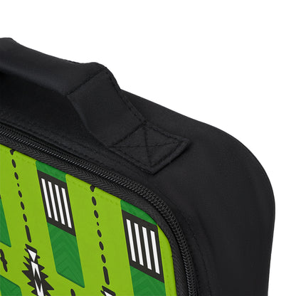 Close-up of an African-inspired lunch bag corner with a fabric handle. The side panel is bright green and features geometric black, white, and dark green patterns like stripes and zigzags. The visible zipper is black and partially open.