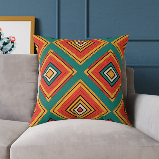 A vibrant home decor piece, this African-inspired pillow features a geometric pattern in red, yellow, orange, and green. It sits on a light gray sofa with a dark blue wall and framed cactus artwork partially visible behind it.